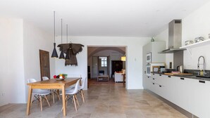 A modern kitchen with white cabinets, a central island, and a dining area with a wooden table and chairs. - Apartment les canisses (UZES)