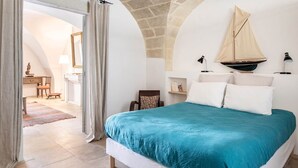 A bedroom with a large bed, a sailboat decoration, a desk with a chair, and a view of a dining area. - Apartment les canisses (UZES)