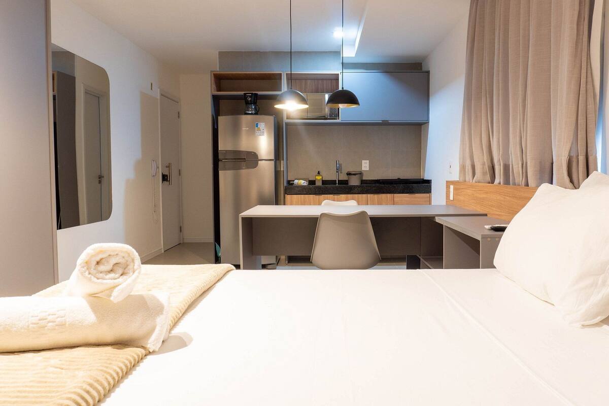 A hotel room with a bed, a desk, a refrigerator, a microwave, and a telephone.