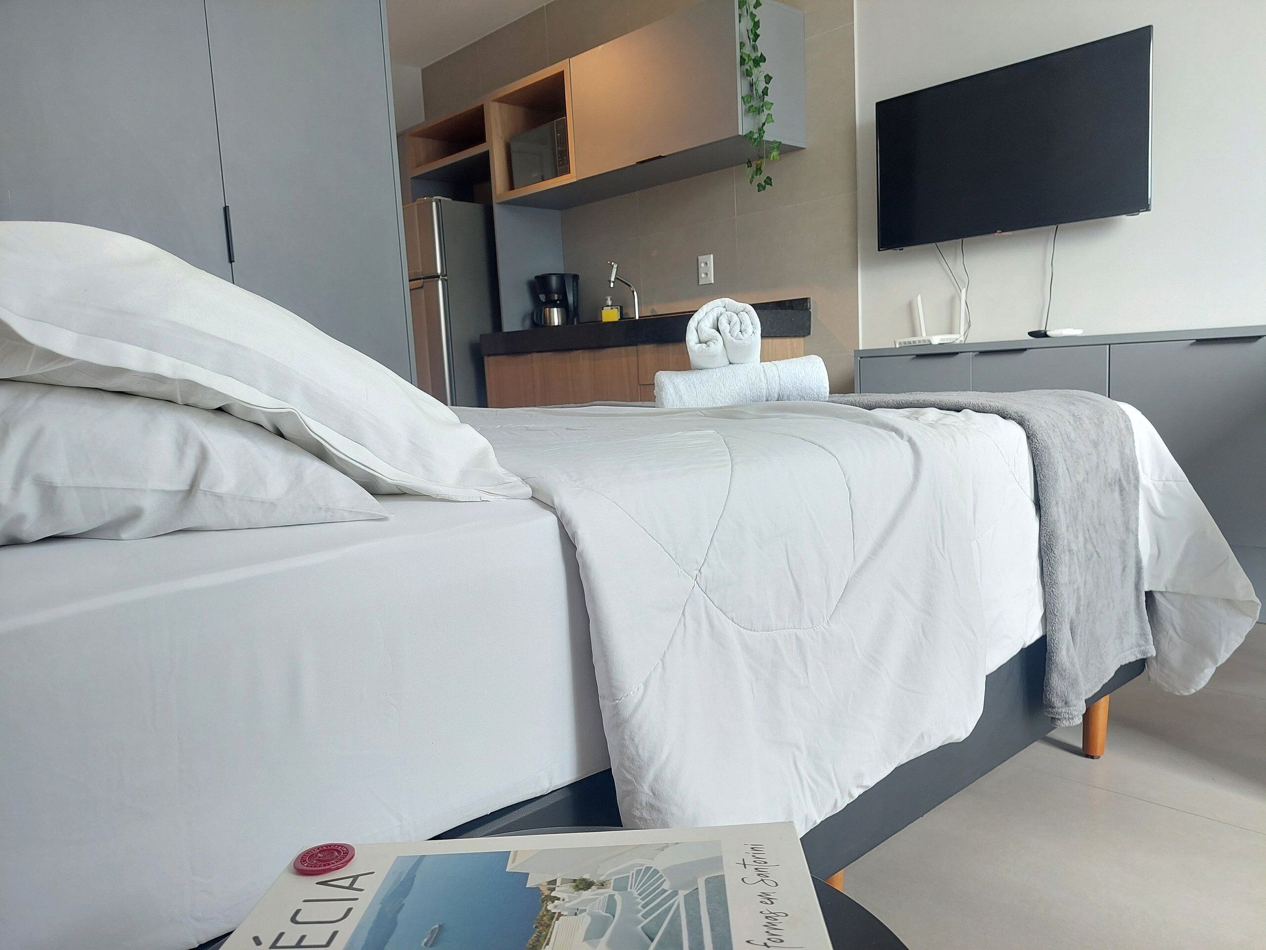Ein modernes Hotelzimmer mit Bett, Flachbildfernseher an der Wand und einer Küchenzeile.