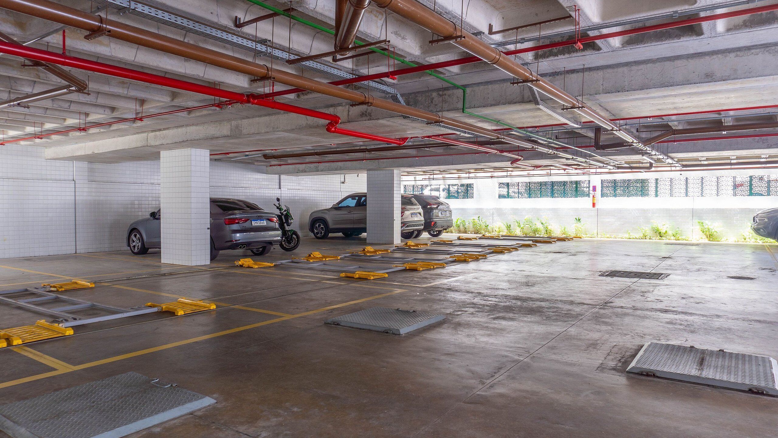 A multi-level parking garage with concrete floors, visible structural beams, and a few parked cars.