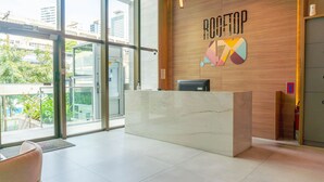 A reception desk with a wooden wall and a large sign reading 'ROOFTOP 170'. - Flats no Rooftop 470 por Yolo (Recife)