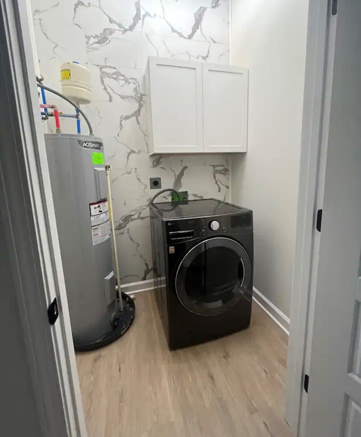 Une buanderie équipée d’un lave-linge et d’un chauffe-eau.
