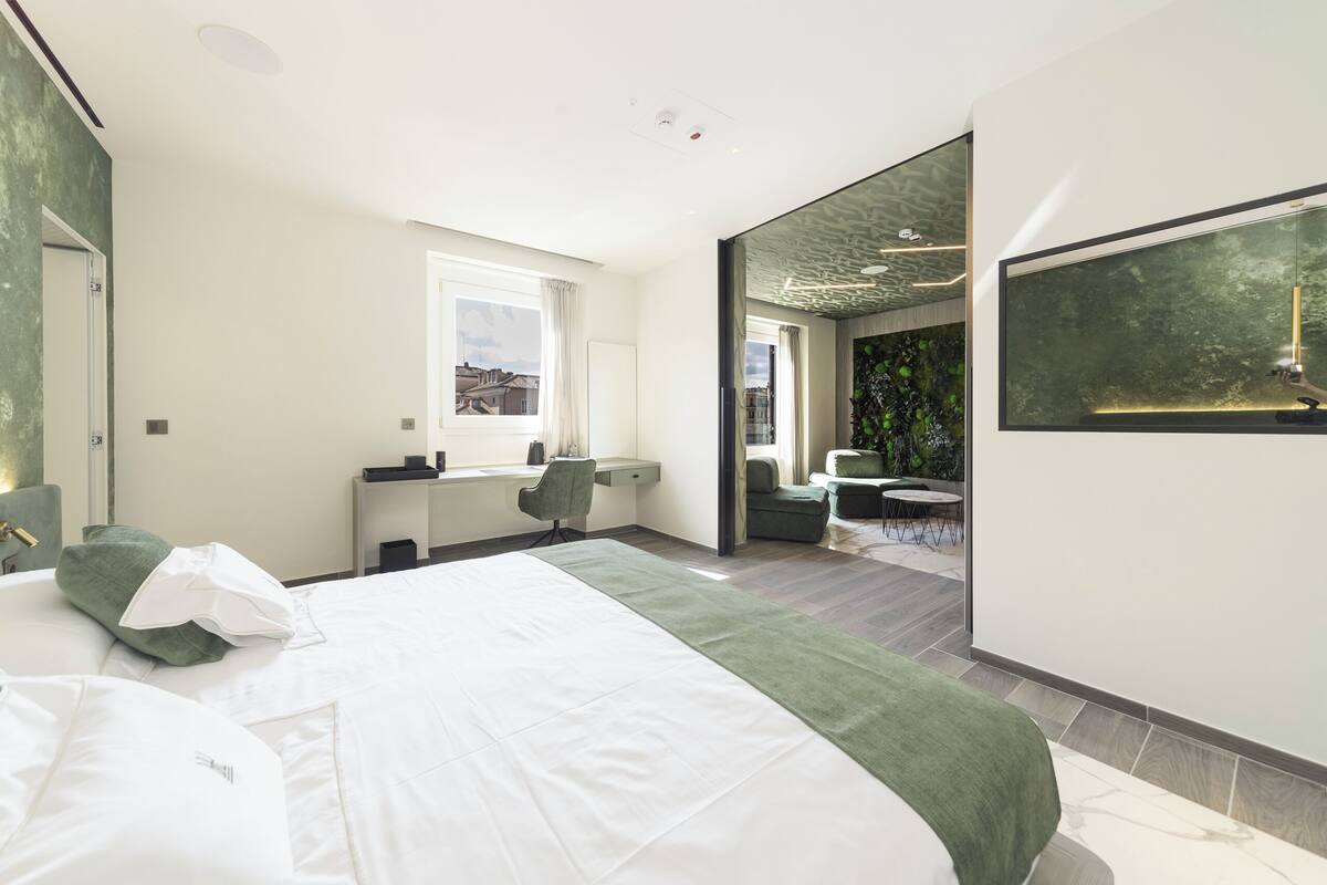 Une chambre d’hôtel moderne, dotée d’un grand lit, d’un bureau et offrant une vue sur le paysage urbain par la fenêtre.