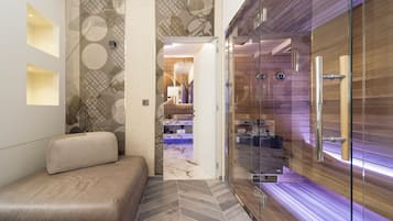 Une salle de bain moderne avec une douche à parois de verre, un canapé beige et un sol à motifs en chevrons.