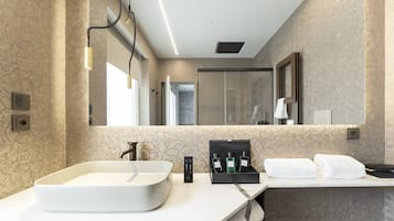 A modern bathroom with a large sink, a mirror, and a shower area.