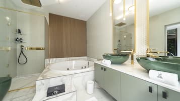 A modern bathroom with a large bathtub, two green vessel sinks, and a walk-in shower.