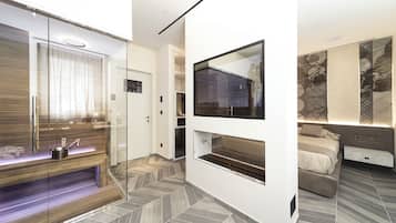 A modern bedroom with a glass shower, a built-in bench, a large mirror, and a bed with a headboard.