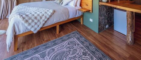 A cozy bedroom with a wooden bed, a small desk, and a green wall.