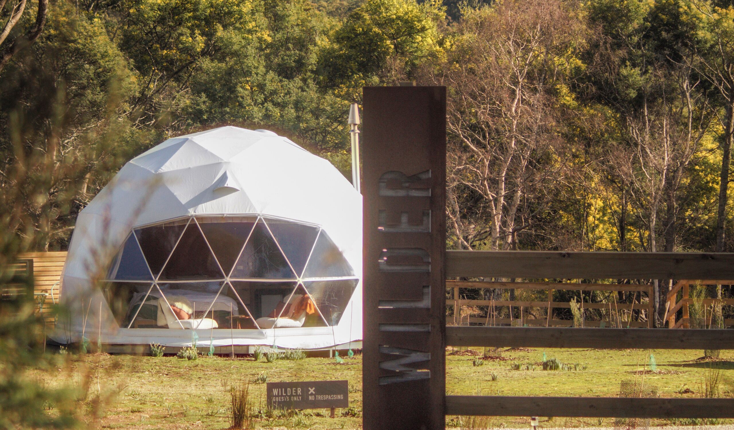 Una estructura de domo geodésico con un cartel que dice 'WILDER GUEST'S ONLY NO TRESPASSING'.