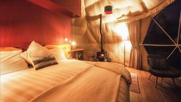 Ein gemütliches Zimmer mit Bett, Sessel, Tisch und Kamin.