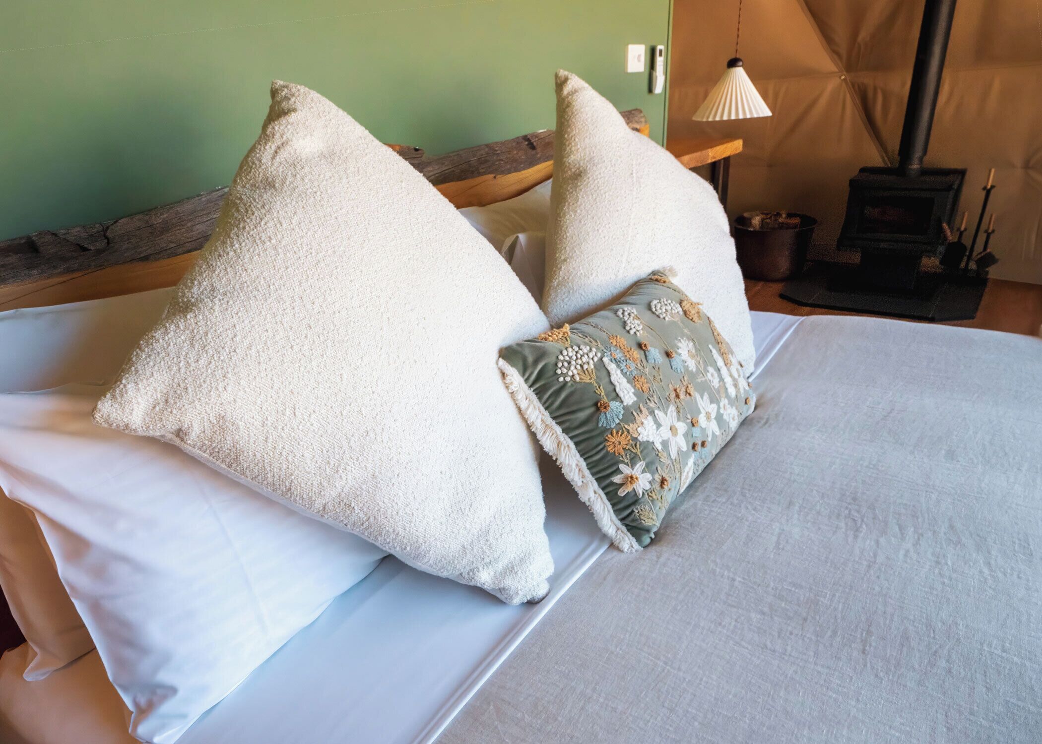 Un letto con cuscini bianchi e un cuscino decorato con ricami floreali.