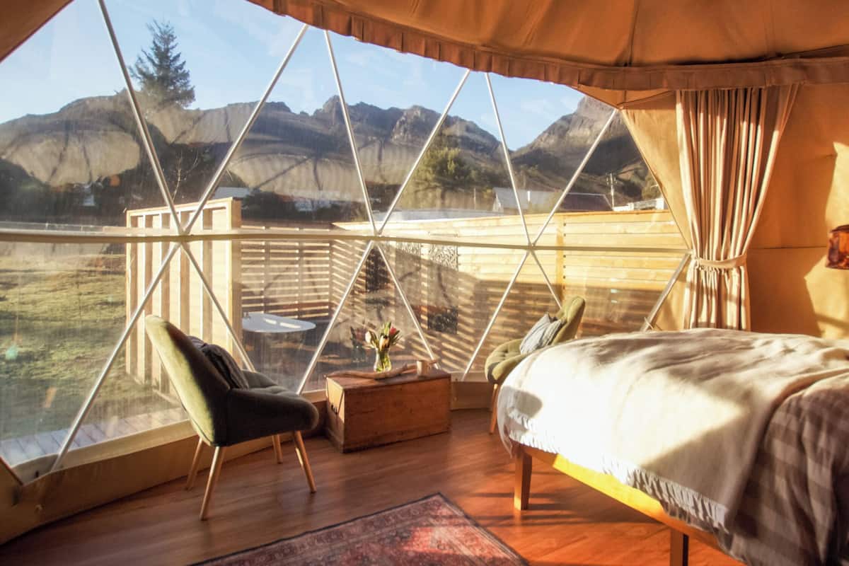 Une chambre dotée d’une grande fenêtre, de meubles en bois et offrant une vue sur les montagnes.