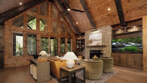 A spacious living room with wooden beams, large windows, a stone fireplace, and a television. - Iron Tree Lodge Blue Ridge GA (Blue Ridge)