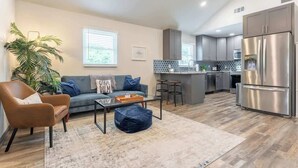 A modern living room with a sofa, coffee table, and a potted plant. - The Good Vibes Cottage (Nashville)