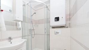 Un baño moderno con ducha de vidrio, lavamanos blanco y retrete.