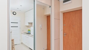 Una cocina moderna con armarios blancos, una puerta de madera y un taburete pequeño.