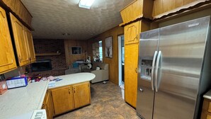 A kitchen with wooden cabinets, a stainless steel refrigerator, a built-in oven, and a tiled floor. - Charming retreat house (Spur)