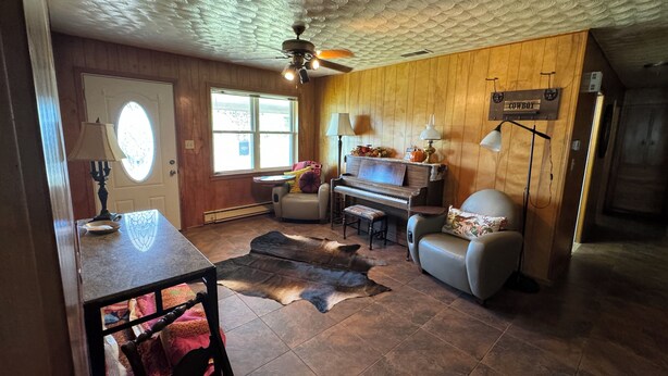 A cozy living room with a piano, a leather couch, and a cowhide rug. - Charming retreat house (Spur)