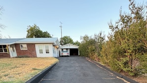 A residential driveway leading to a garage, surrounded by a lawn and trees. - Charming retreat house (Spur)