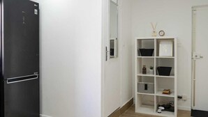 A compact kitchen with a black refrigerator, a white cabinet with shelves, and a wooden floor.