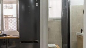 A modern kitchen with a black refrigerator, wooden cabinets, and a wooden countertop.