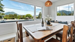 A dining area with a wooden table, chairs, a bottle, and a vase of flowers.