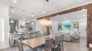 A spacious dining area with a wooden table and chairs, a chandelier, and a view of the living room. - Bike, EV Charger, New Rental! Golf Cart Included, Pool, 30A (Santa Rosa Beach)