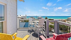 A balcony with white chairs, a yellow bench, and a view of the ocean and beach. - Outdoor TV, Bikes, Gulf Views, Prime 30A Location, Large Private Pool (Santa Rosa Beach)