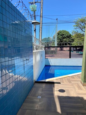 A swimming pool area with tiled walls, a wooden deck, and a fenced enclosure. - Flat 10 Residencial Praça 19 by La Playa (Ipojuca)