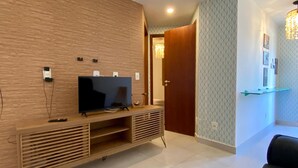 A modern living room with a wooden entertainment unit, a flat-screen TV, and a dark-colored sofa.