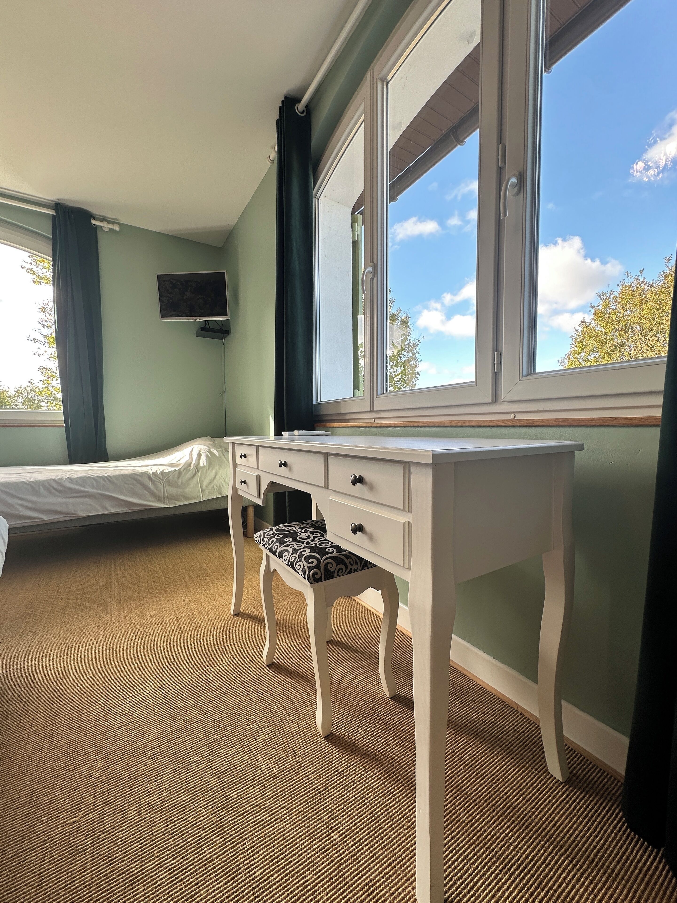 Un dormitorio con una cama, un escritorio y una ventana.