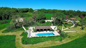 An aerial view of a villa with a swimming pool, surrounded by lush greenery and a hilly landscape. - Luxury Holiday Home Paulhiac - Large Pool (Paulhiac)