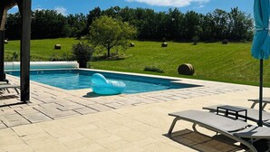 A swimming pool with a blue inflatable float, lounge chairs, and a covered area. - Luxury Holiday Home Paulhiac - Large Pool (Paulhiac)