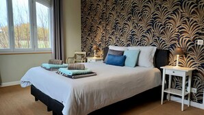 A bedroom with a large bed, a nightstand, a chair, and a window. - Luxury Holiday Home Paulhiac - Large Pool (Paulhiac)