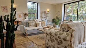 A living room with a sofa, armchair, coffee table, and a cactus plant. - Le Champ du Roy (Chasse-sur-Rhône)