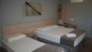 Habitación de hotel con dos camas, cabecero de madera, un escritorio, una silla, un armario y un equipo de aire acondicionado.