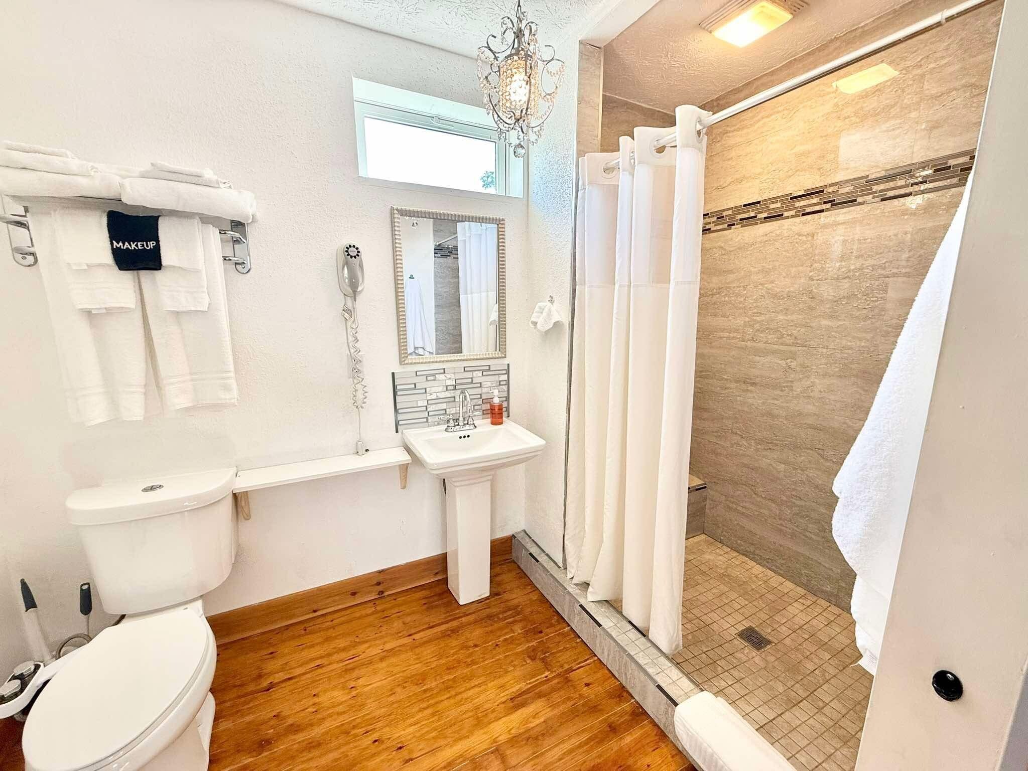 Une salle de bain comprenant des toilettes, un lavabo et un espace douche.