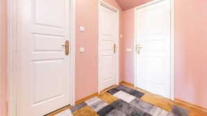 A hallway with two white doors, pink walls, and a patterned rug on the floor. - DICTUMFACTUM RESIDENCE 2BedRoom (Tallinn)