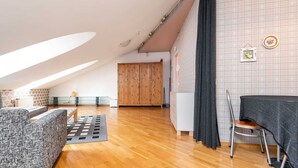 A spacious loft apartment with a high ceiling, wooden flooring, a dining area with a table and chairs, and a large wooden wardrobe. - DICTUMFACTUM RESIDENCE 2BedRoom (Tallinn)