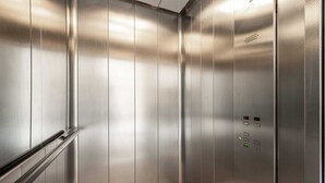A metallic elevator interior with a handrail and control panel. - DICTUMFACTUM RESIDENCE 2BedRoom (Tallinn)