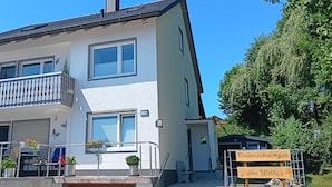 A two-story house with a balcony, a garage door, and a sign indicating it's a rental property. - Gemütliche Naturnahe Ferienwohnung in Oberbayern "Am Weiher" (Denklingen)