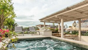 A rooftop pool area with a hot tub, lounge chairs, and a pergola. - Casa Charlies Can (Cartagena)