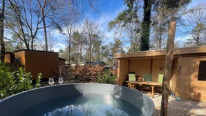 A hot tub in a wooden cabin with a view of trees and a wooden deck. - Forest Finest, luxury chalet with HOT TUB beautiful canopy and beautiful garden (Hoenderloo)