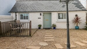 Une petite maison de campagne à un seul étage, dotée d’un toit en pente, d’un porche en bois et d’un chemin de gravier menant à l’entrée.