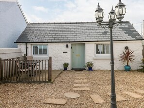 Une petite maison de campagne à un seul étage, dotée d’un toit en pente, d’un porche en bois et d’un chemin de gravier menant à l’entrée.