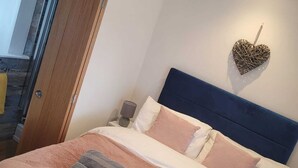 A bedroom with a bed, pillows, a heart-shaped decoration, and a nightstand. - Dog Friendly 18th Century Cottage (Saundersfoot)