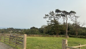 A grassy field with a wooden fence, trees, and a distant view of houses. - Dog Friendly 18th Century Cottage (Saundersfoot)