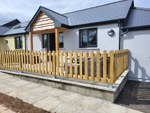 A modern house with a wooden fence, a covered porch, and a paved driveway. - Pet Friendly Cottage with Sea Views (Saundersfoot)