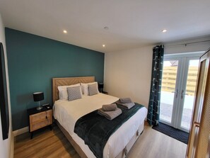 A bedroom with a bed, a nightstand, a lamp, and a view of the outside through a sliding door.